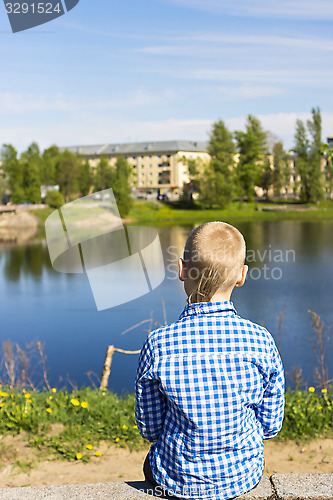Image of Ten year boy looks on city from river shore