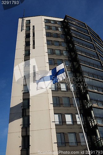 Image of fluttering national flag of Finland beside modern building