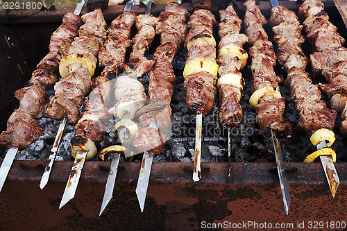 Image of grilled meat on metal skewers cooking on a coal