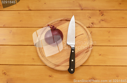 Image of Red onion with a knife on a chopping board