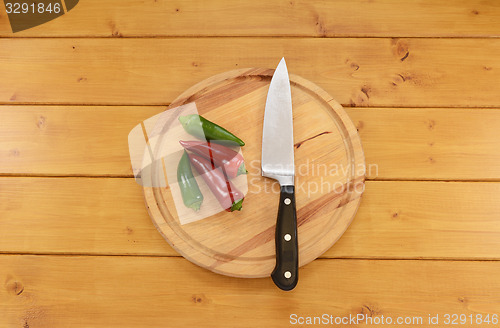 Image of Red and green chilis with a knife on a chopping board