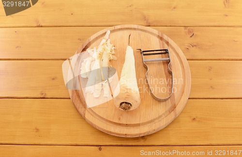 Image of Peeled parsnip with vegetable peeler on a chopping board