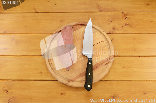 Image of Sweet potato with a knife on a chopping board