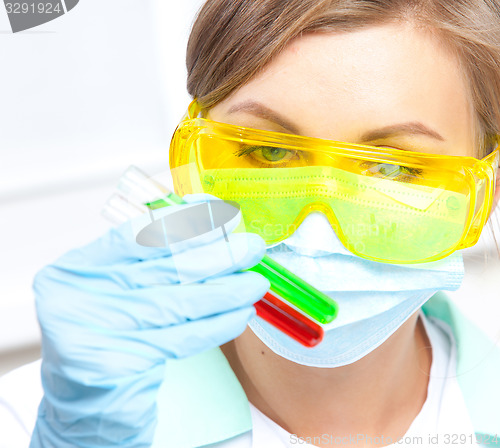 Image of doctor in a mask examines test tubes