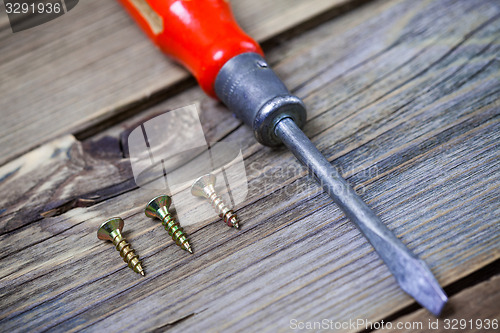 Image of screws and old screwdriver with a red wooden handle