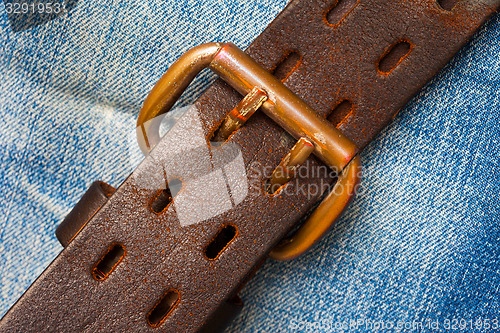 Image of clasped leather belt on jeans background