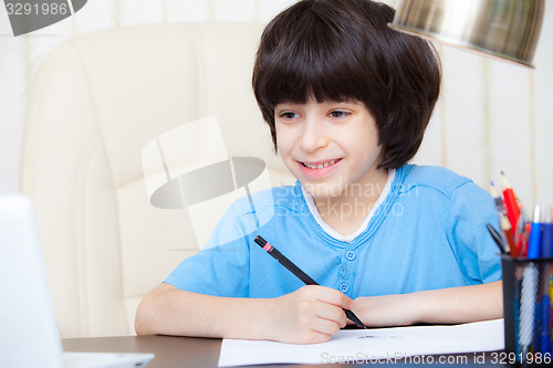 Image of smiling child doing homework with computer