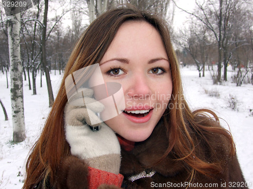 Image of The girl in the winter in park speaks by phone