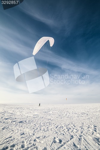 Image of Kiteboarder with blue kite on the snow