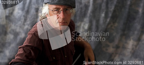 Image of blue eyed man with glasses and grey hair wearing cap
