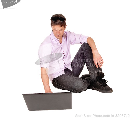 Image of Man working on laptop of floor.