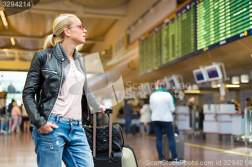 Image of Female traveller checking flight departures board.