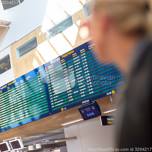 Image of Female traveller checking flight departures board.