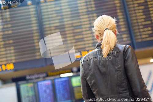 Image of Female traveller checking flight departures board.