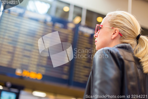Image of Female traveller checking flight departures board.