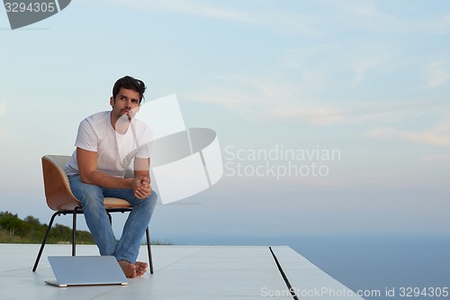 Image of relaxed young man at home on balcony