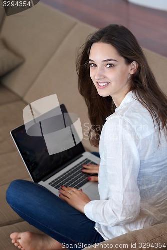 Image of relaxed young woman at home working on laptop computer