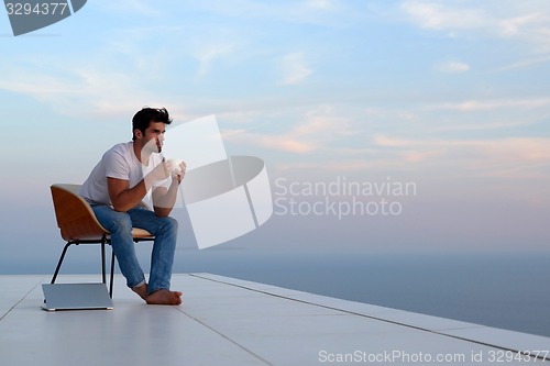 Image of relaxed young man at home on balcony