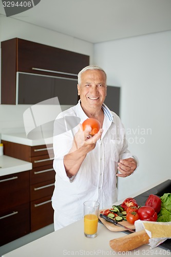 Image of man cooking at home preparing salad in kitchen