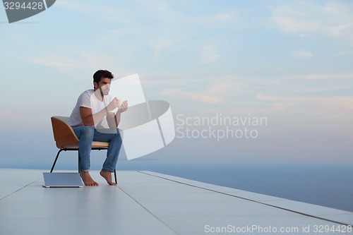 Image of relaxed young man at home on balcony