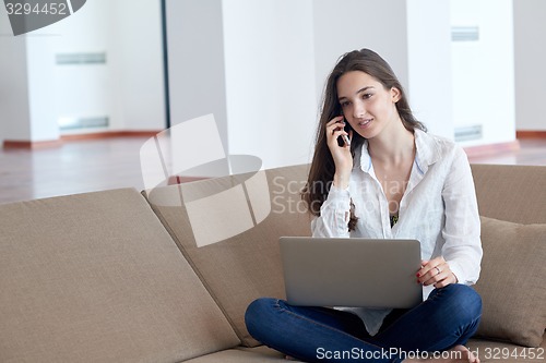 Image of relaxed young woman at home working on laptop computer