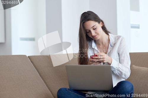 Image of relaxed young woman at home working on laptop computer