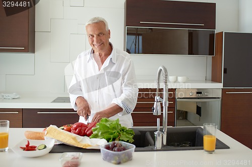 Image of man cooking at home preparing salad in kitchen