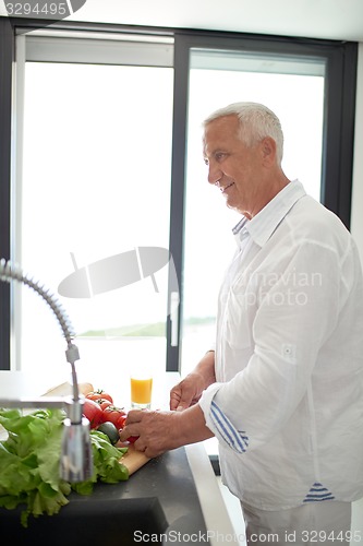 Image of man cooking at home preparing salad in kitchen