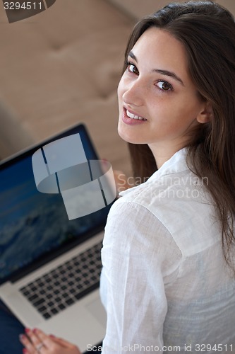 Image of relaxed young woman at home working on laptop computer