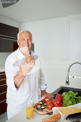 Image of man cooking at home preparing salad in kitchen