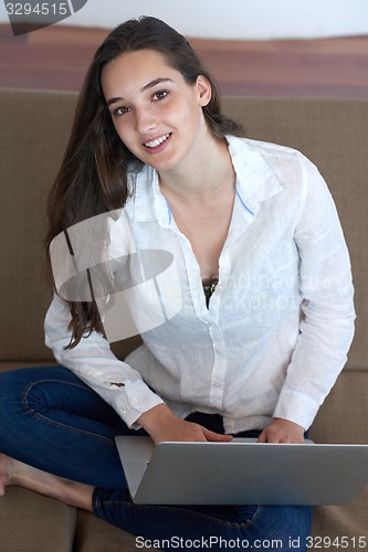 Image of relaxed young woman at home working on laptop computer