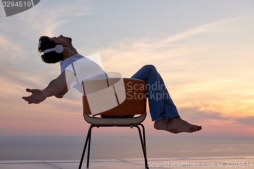 Image of relaxed young man at home on balcony