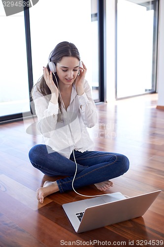 Image of relaxed young woman at home working on laptop computer