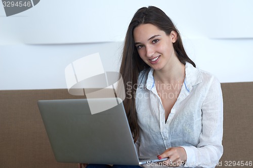 Image of relaxed young woman at home working on laptop computer