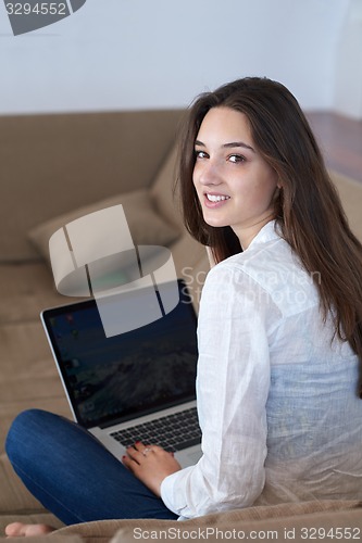 Image of relaxed young woman at home working on laptop computer