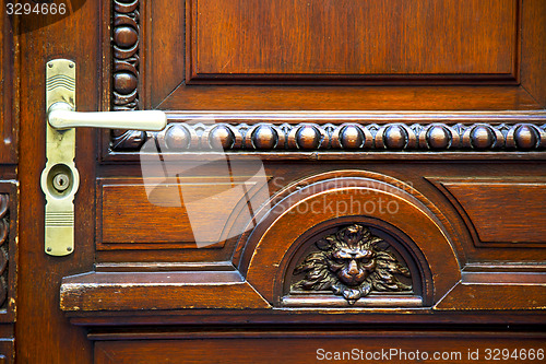 Image of abstract   brass brown knocker in a   closed wood door    lugano