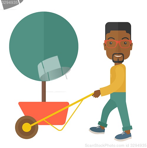 Image of Young african man pushing the cart with tree.