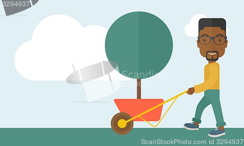 Image of Young african man pushing the cart with tree.