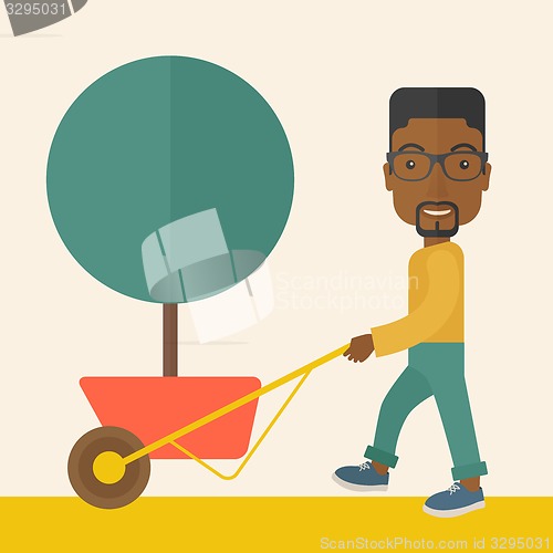 Image of Young african man pushing the cart with tree.