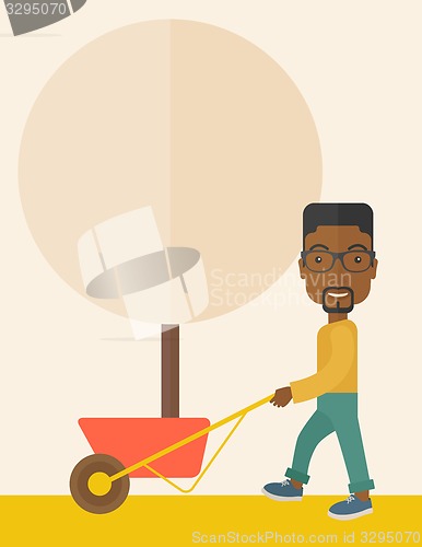 Image of Young african man pushing the cart with tree.