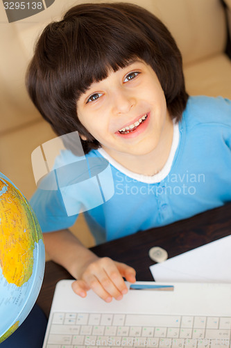 Image of smiling boy doing homework on computer