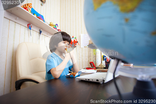 Image of schoolboy with a laptop eating apple