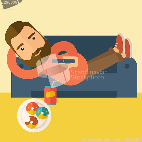 Image of Man lying in the sofa holding a remote.