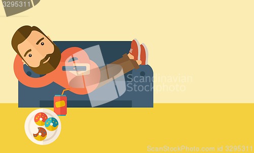 Image of Man lying in the sofa holding a remote.