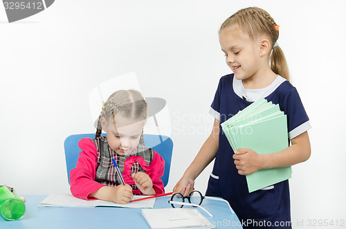 Image of Girl teacher pointer indicates something in a notebook student