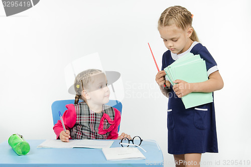 Image of Teacher seeks pupil notebook pile of notebooks