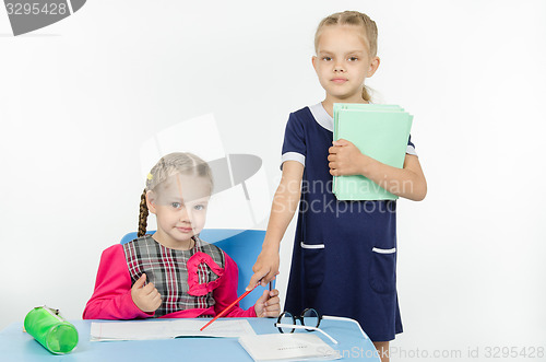 Image of Girl teacher points at student notebook