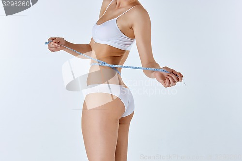 Image of Woman holding meter measuring perfect shape of her beautiful body 