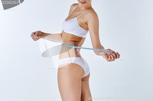 Image of Woman holding meter measuring perfect shape of her beautiful body 