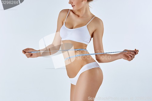 Image of Woman holding meter measuring perfect shape of her beautiful body 